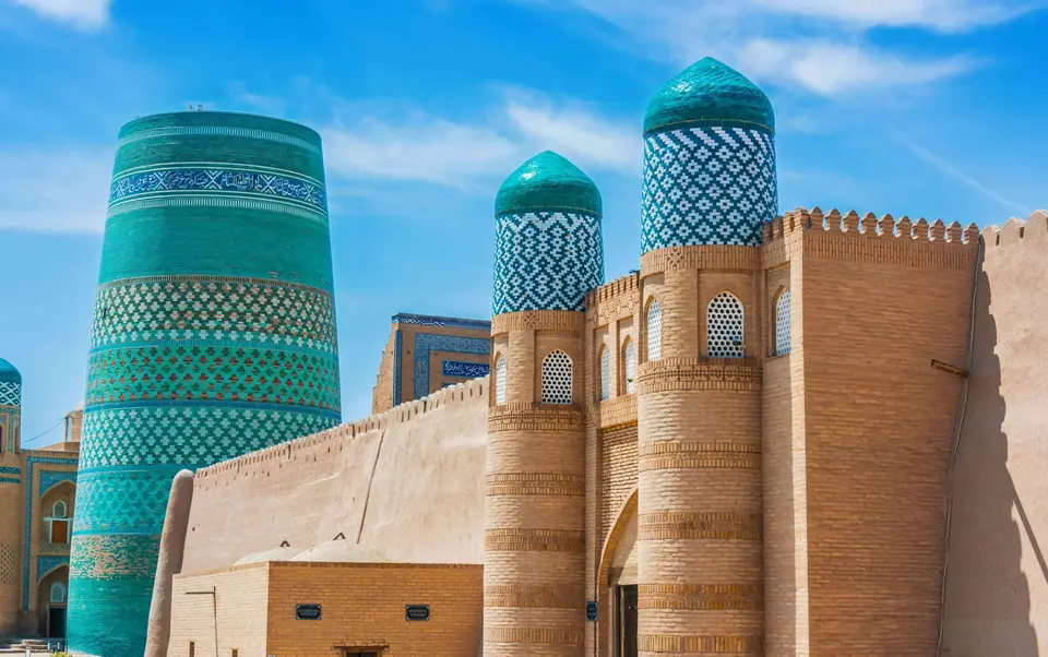 Turquoise-tiled Kalta Minor minaret beside the mud-brick walls of Khiva